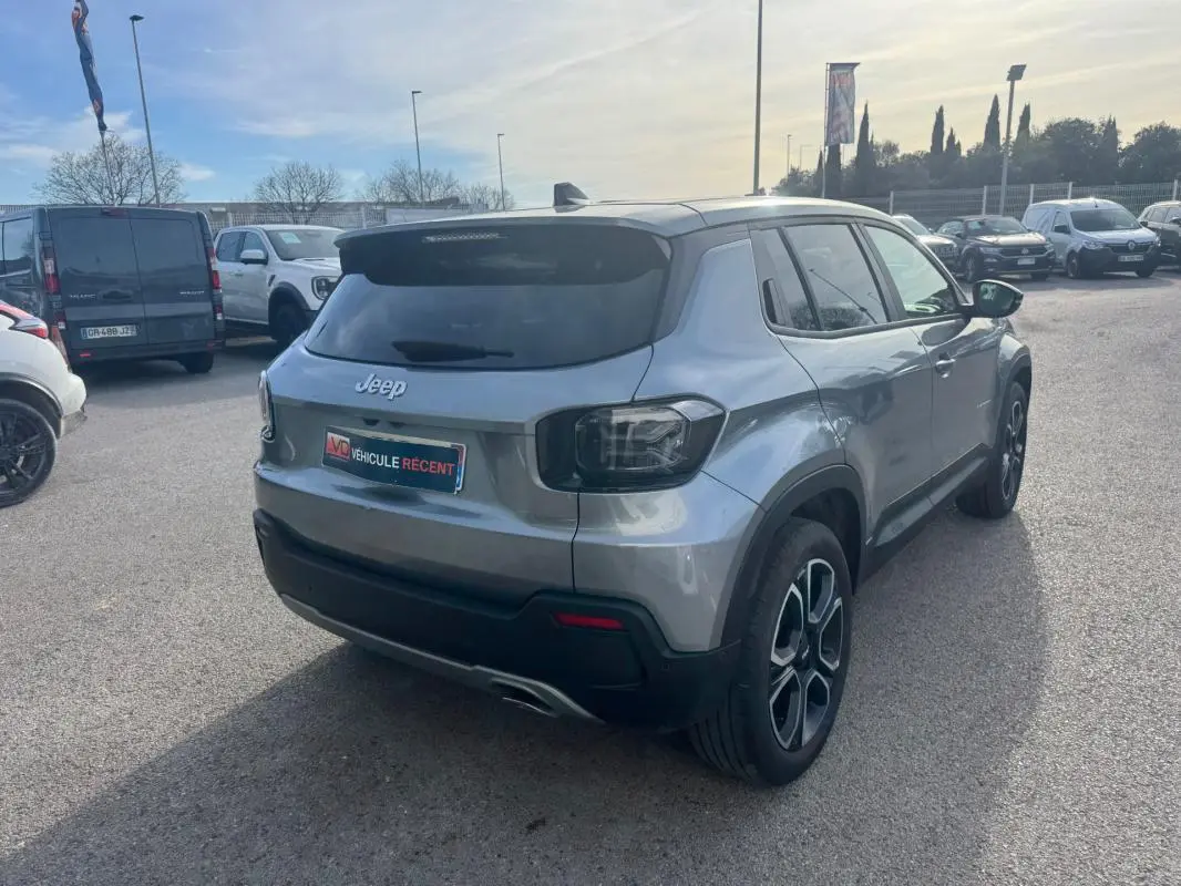 Jeep Avenger gris en 3/4 arrière droit, avec feux arrière sombres et jantes alliage distinctives.