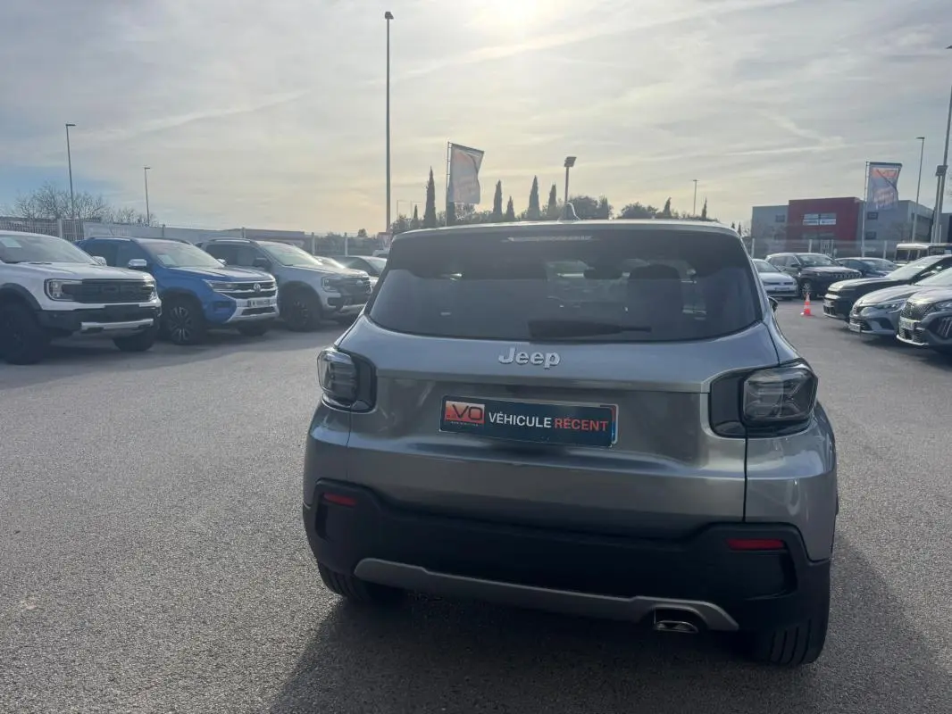 Vue arrière d'un Jeep Avenger gris 2025 garé en extérieur, avec feux arrière foncés et plaque "Véhicule récent".
