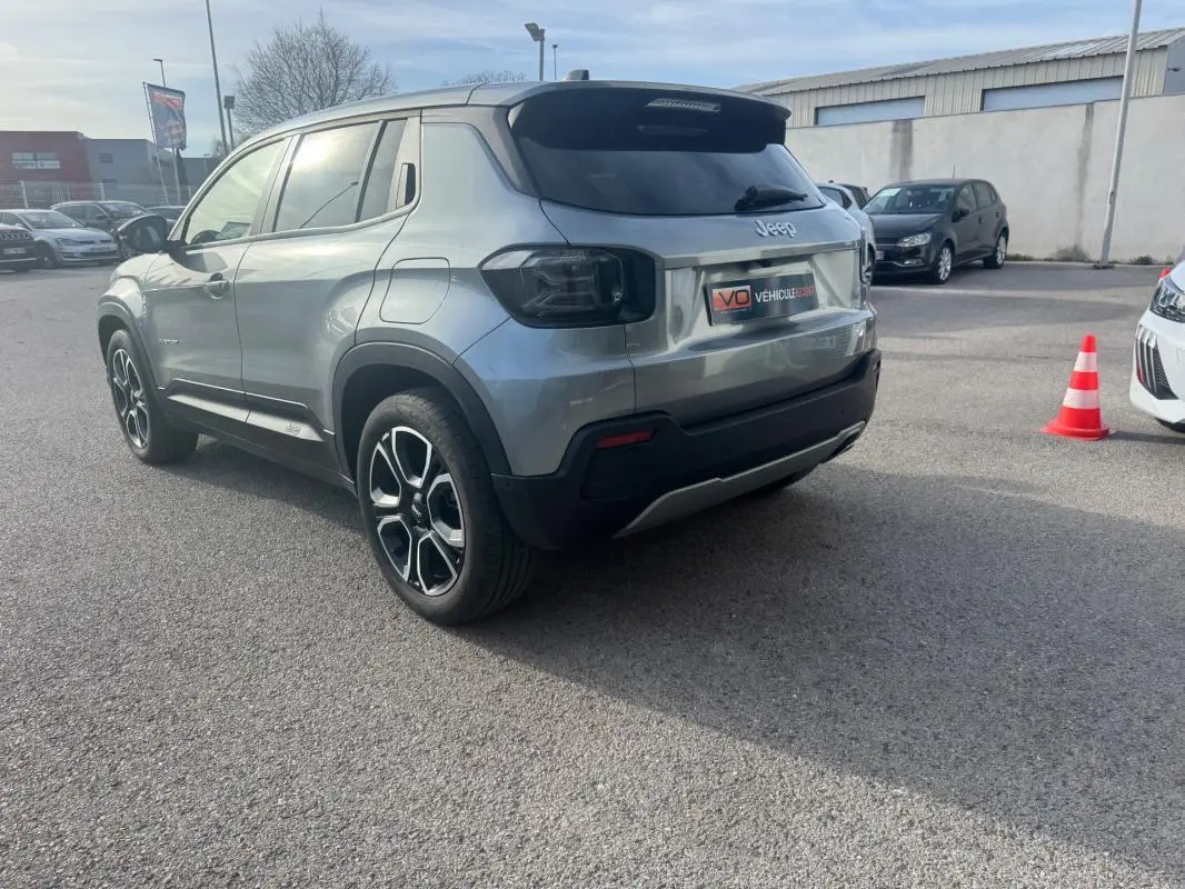 Jeep Avenger gris vue 3/4 arrière droit, avec jantes noires et détails noirs contrastants sur le pare-chocs.