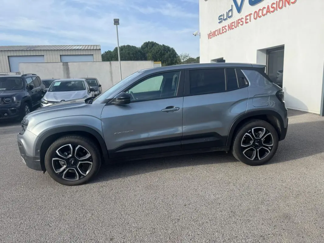 Vue de profil côté gauche d'un Jeep Avenger gris 2025 avec jantes noires et détails noirs contrastants.