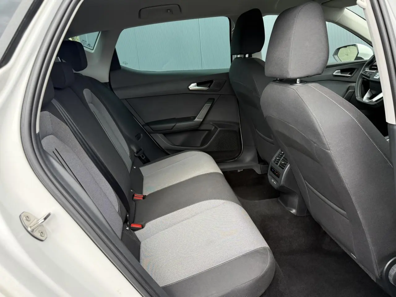 Vue intérieure côté gauche des sièges arrière gris et noirs d'une SEAT LEON blanche de 2025.