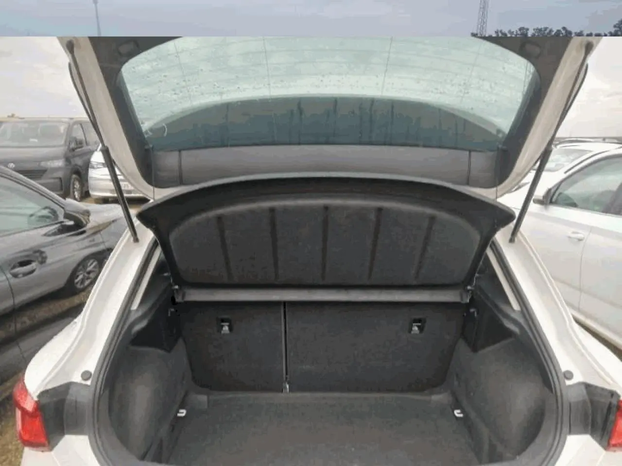 Coffre ouvert vu de l'arrière d'une SEAT Leon blanche, montrant l'espace de chargement vide et les feux arrière.
