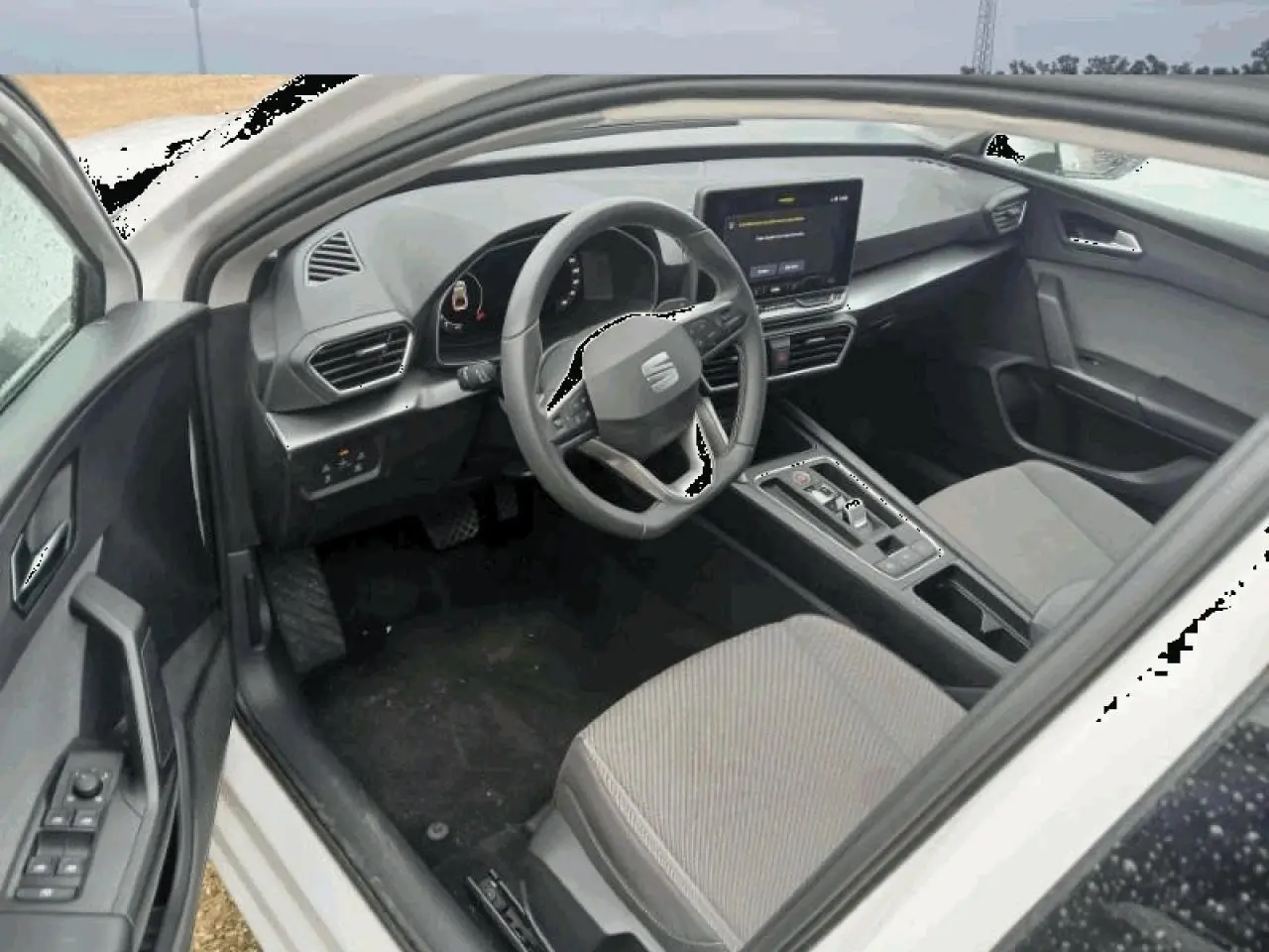 Intérieur de la SEAT Leon 2025 blanc, vue côté conducteur, tableau de bord digital et volant multifonction cuir.