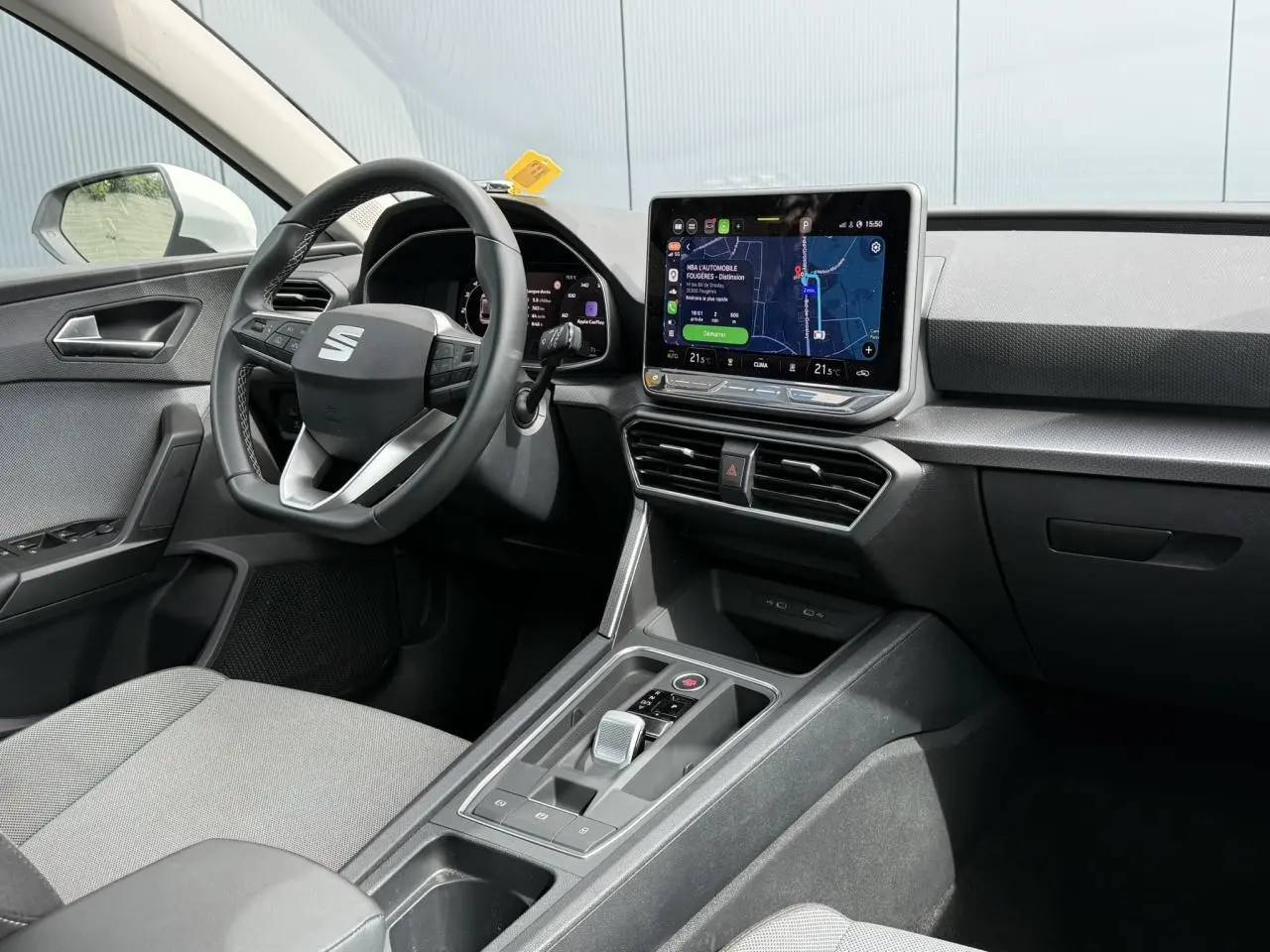 Vue intérieure côté conducteur du SEAT Leon 2025, tableau de bord noir avec écran tactile central et volant multifonction.