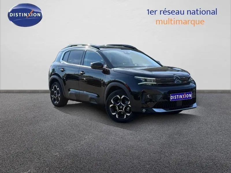 Vue 3/4 avant du Citroën C5 Aircross noir Perla Nera avec jantes alu et barres de toit visibles sur fond neutre.