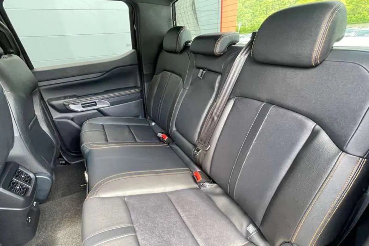 Vue latérale intérieure sur la banquette arrière en cuir noir avec surpiqûres jaunes du Ford Ranger Wildtrak Plus 2025.
