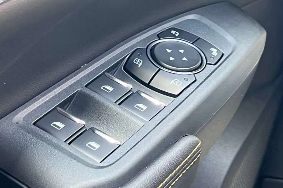 Gros plan sur les commandes des vitres électriques et rétroviseurs du côté gauche intérieur du Ford Ranger Wildtrak Plus noir agate.