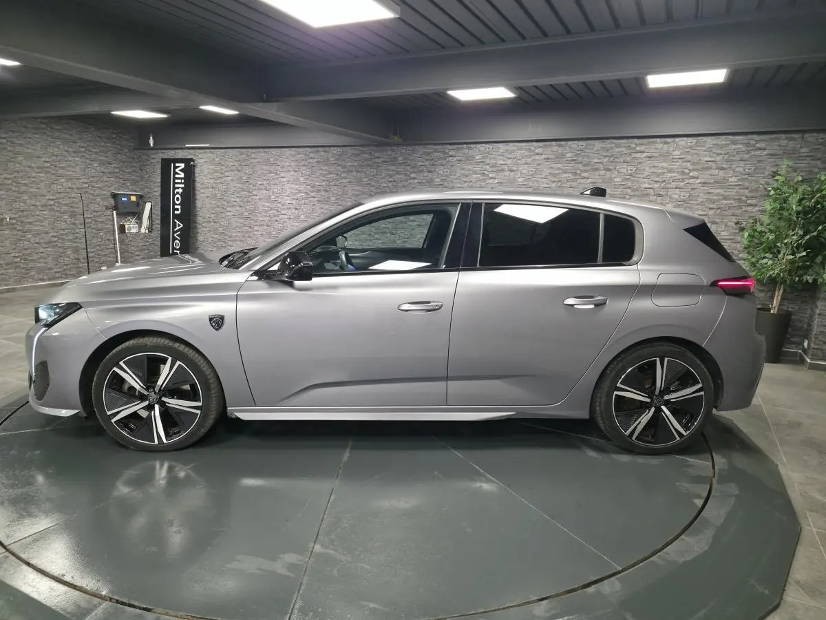 Peugeot 308 gris métallisé vue de profil côté gauche, avec jantes alliage noires et vitres surteintées.