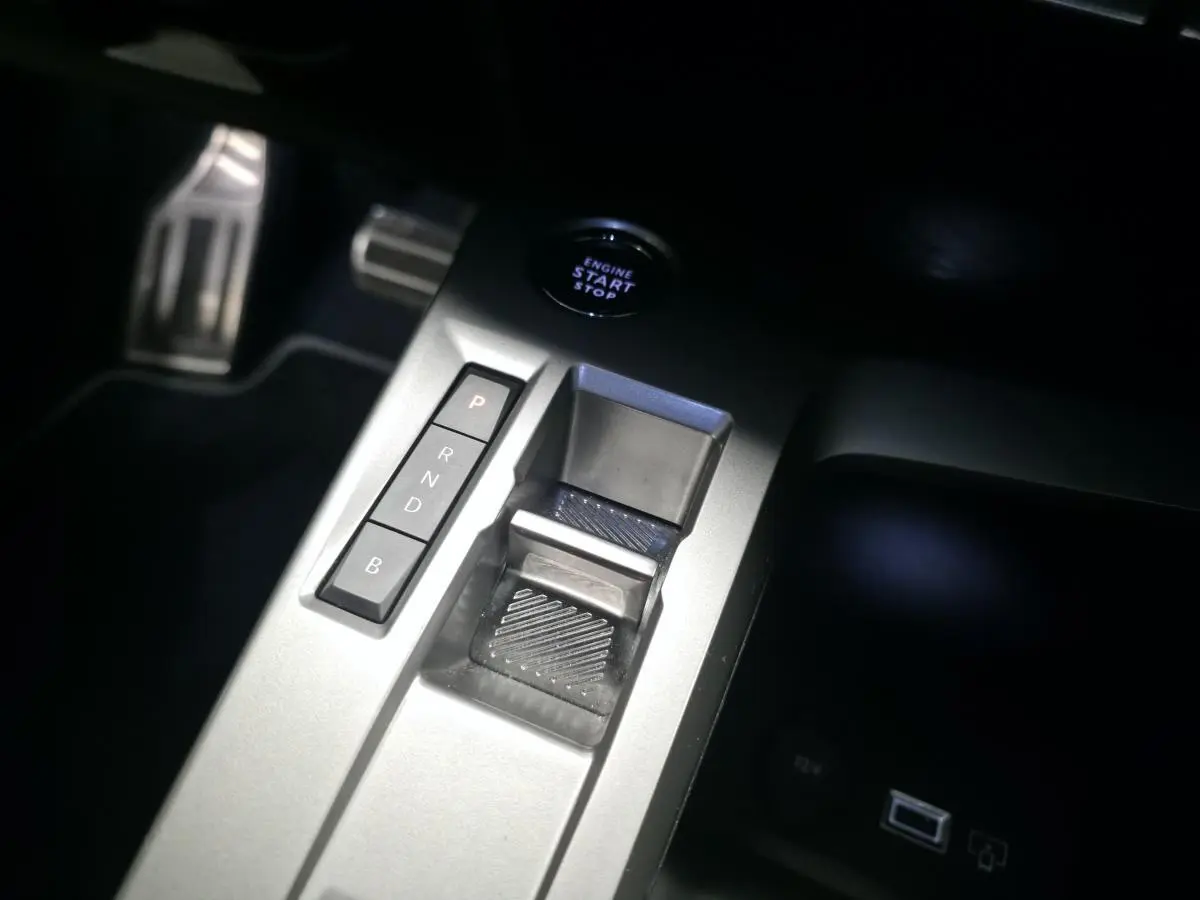 Gros plan sur la console centrale grise de la Peugeot 308 2024 avec sélecteur de boîte auto et bouton start/stop.