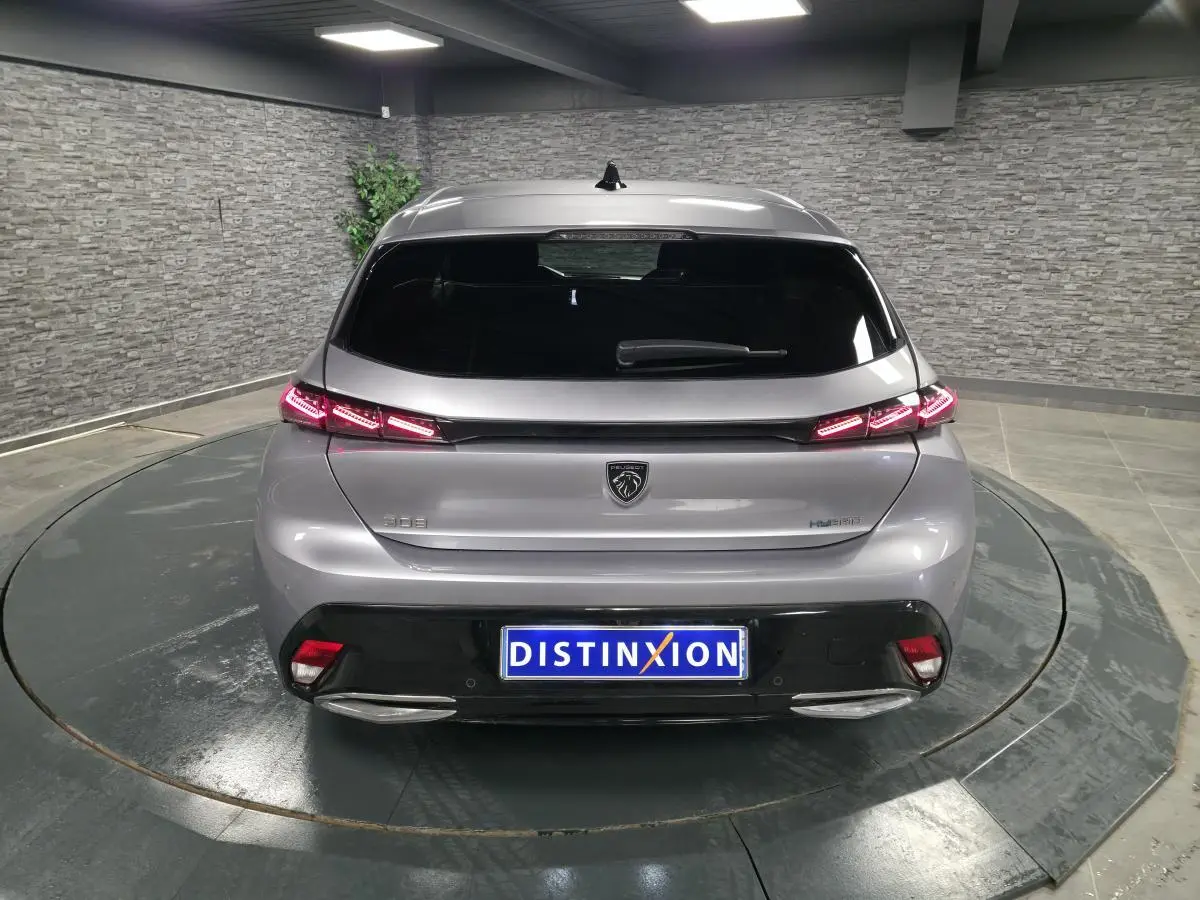 Vue arrière d'une Peugeot 308 gris métallisé 2024 avec feux arrière LED en forme de griffe et logo lion central.