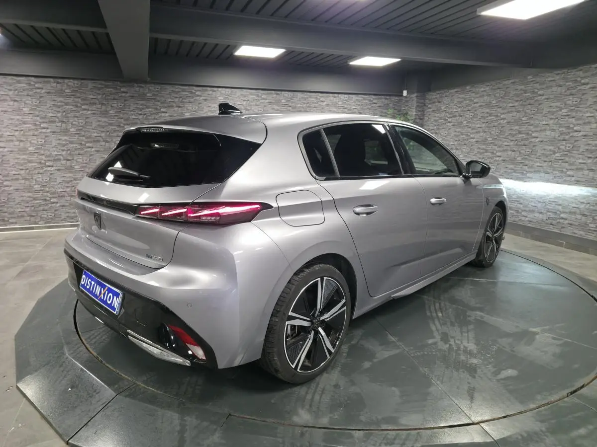 Vue 3/4 arrière droite de la Peugeot 308 GT hybride rechargeable gris métallisé avec feux arrière LED distinctifs.