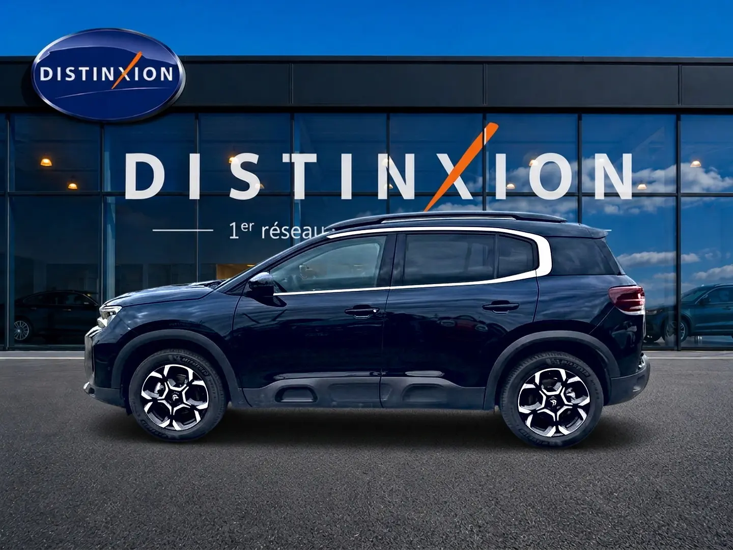 Profil droit du Citroën C5 Aircross noir 2025 avec jantes alu et barres de toit visibles devant une vitrine Distinxion.