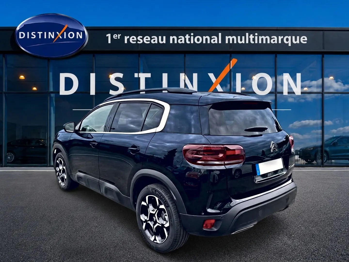 Citroën C5 Aircross noir vue 3/4 arrière droit, avec jantes alu et barres de toit devant showroom Distinxion.