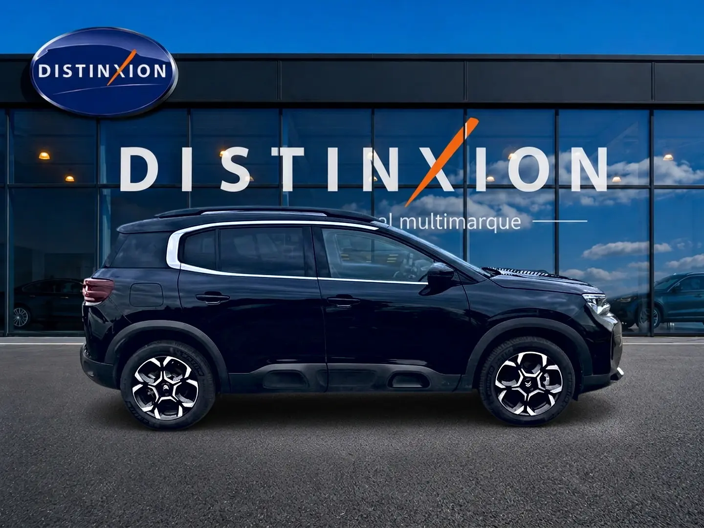 Profil côté gauche du Citroën C5 Aircross noir 2025 avec jantes alu et barres de toit visibles devant une vitrine Distinxion.