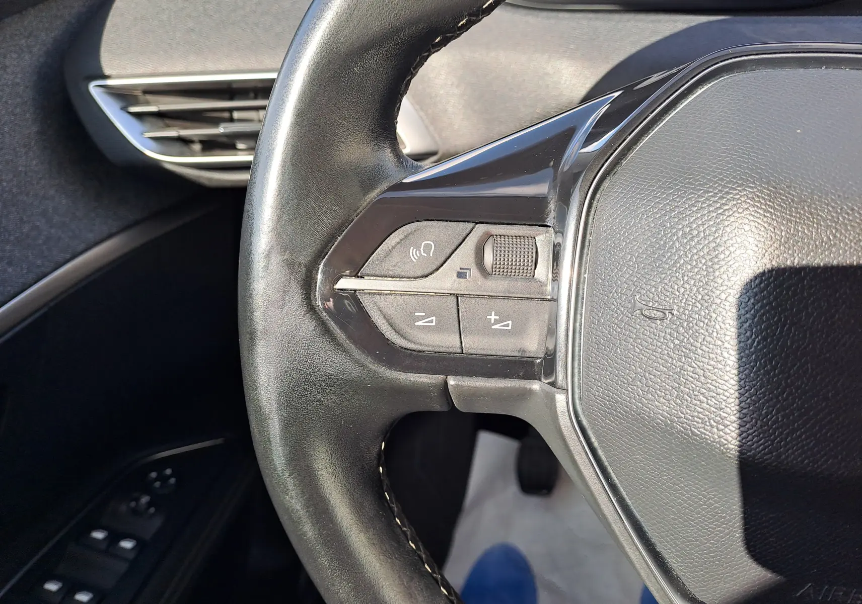 Gros plan sur le volant en cuir noir du Peugeot 3008 2019, montrant les commandes audio à gauche.