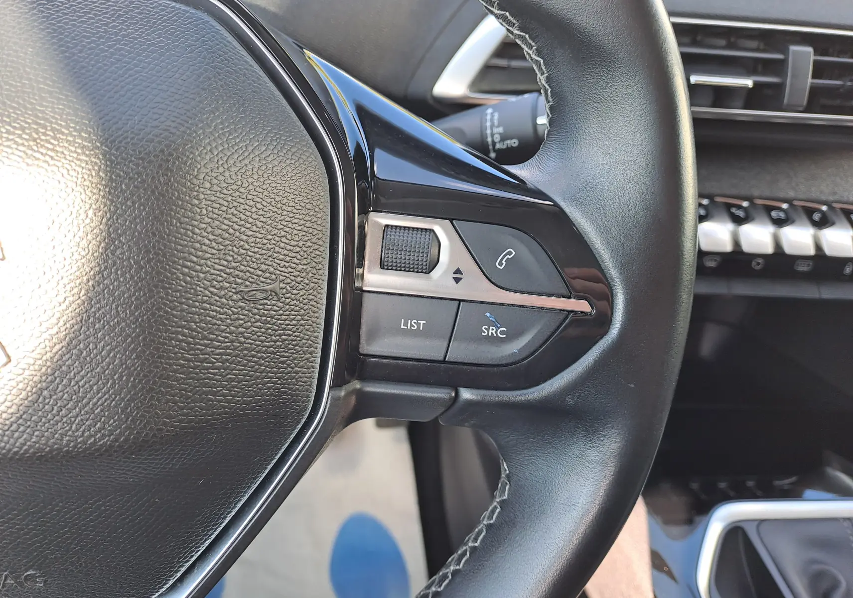 Gros plan sur les commandes gauche du volant cuir noir du Peugeot 3008 2019 finition Allure en Metallic Cooper.