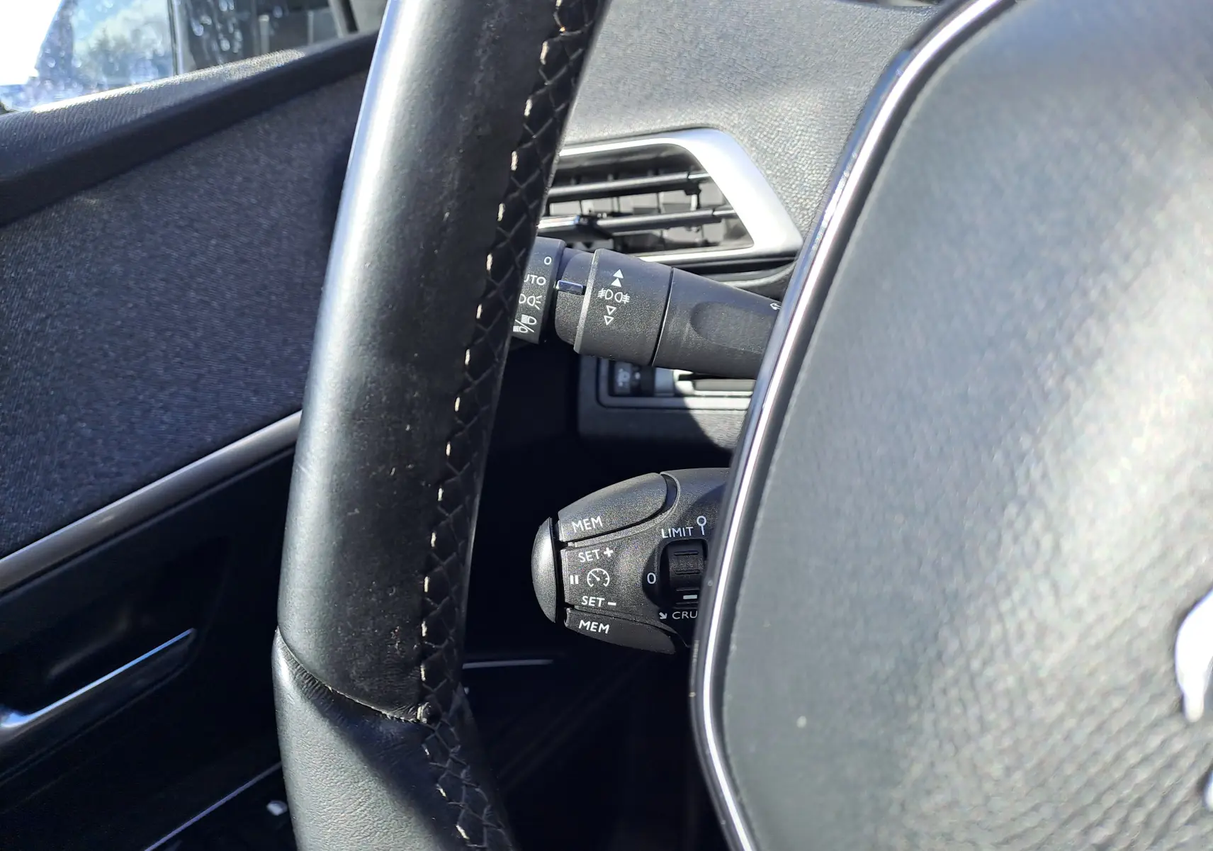 Gros plan sur le volant noir et les commandes de régulateur de vitesse du Peugeot 3008 Metallic Cooper, intérieur gris.