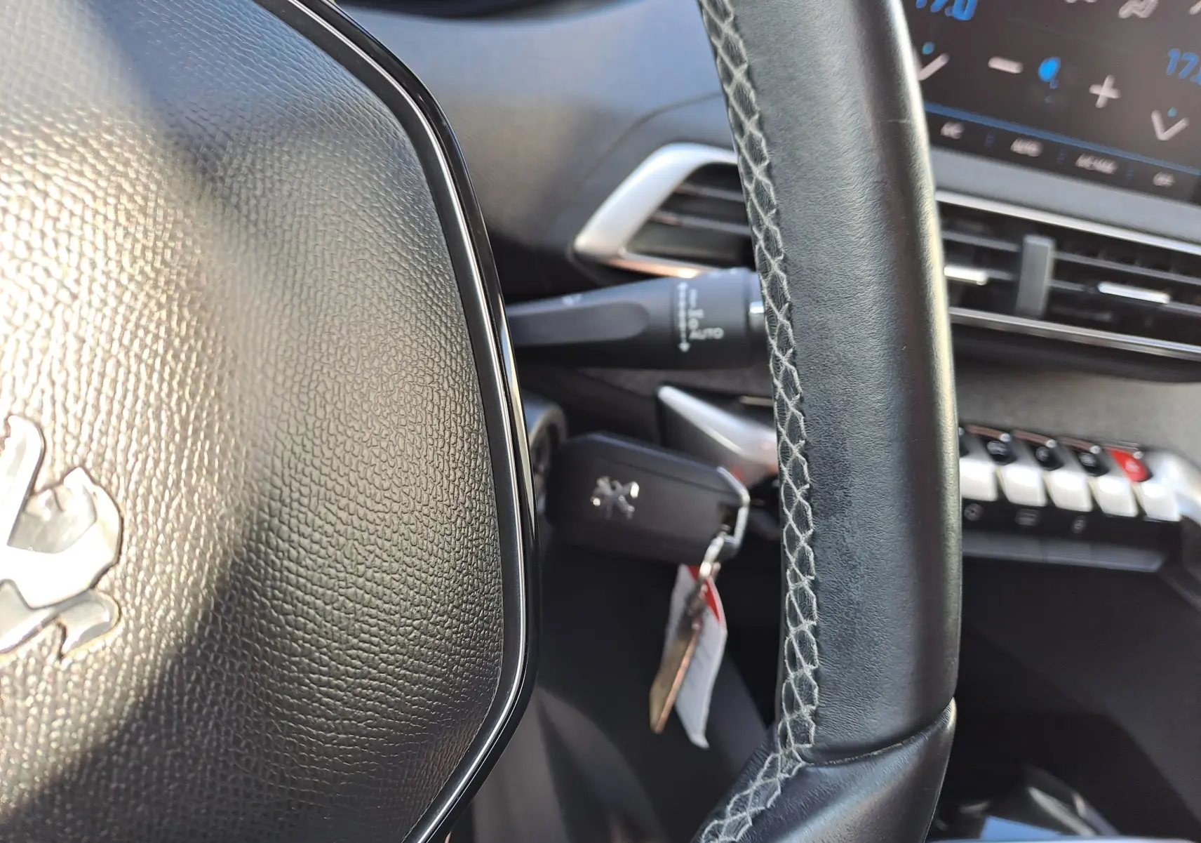 Gros plan sur le volant en cuir noir avec logo Peugeot et tableau de bord numérique en arrière-plan du 3008 Metallic Cooper.