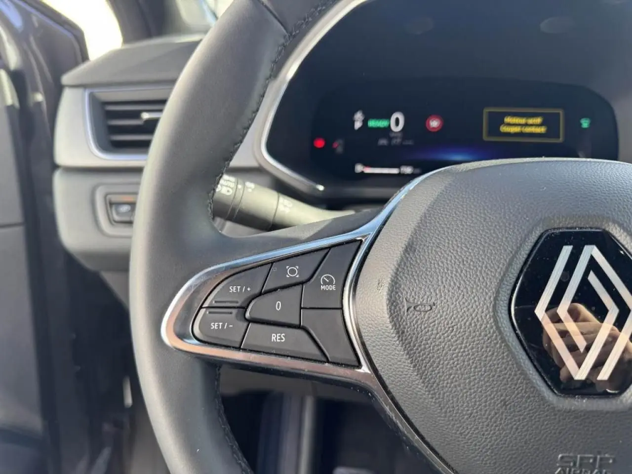 Gros plan sur le volant côté gauche du Renault Captur gris Cassiopée 2025 avec commandes intégrées et tableau de bord numérique.