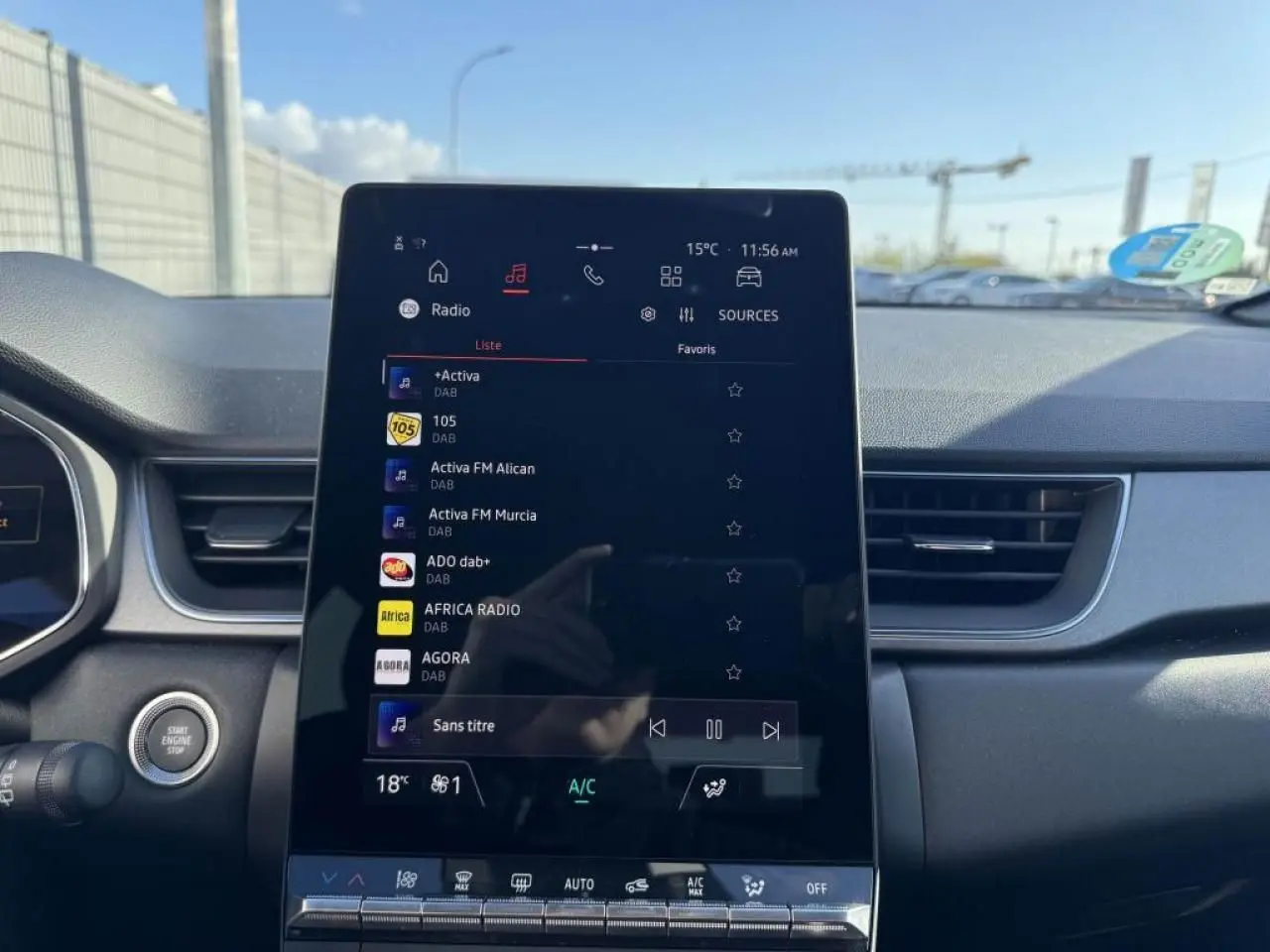 Vue intérieure centrée sur l'écran tactile vertical du tableau de bord du Renault Captur gris Cassiopée, avec commandes visibles.