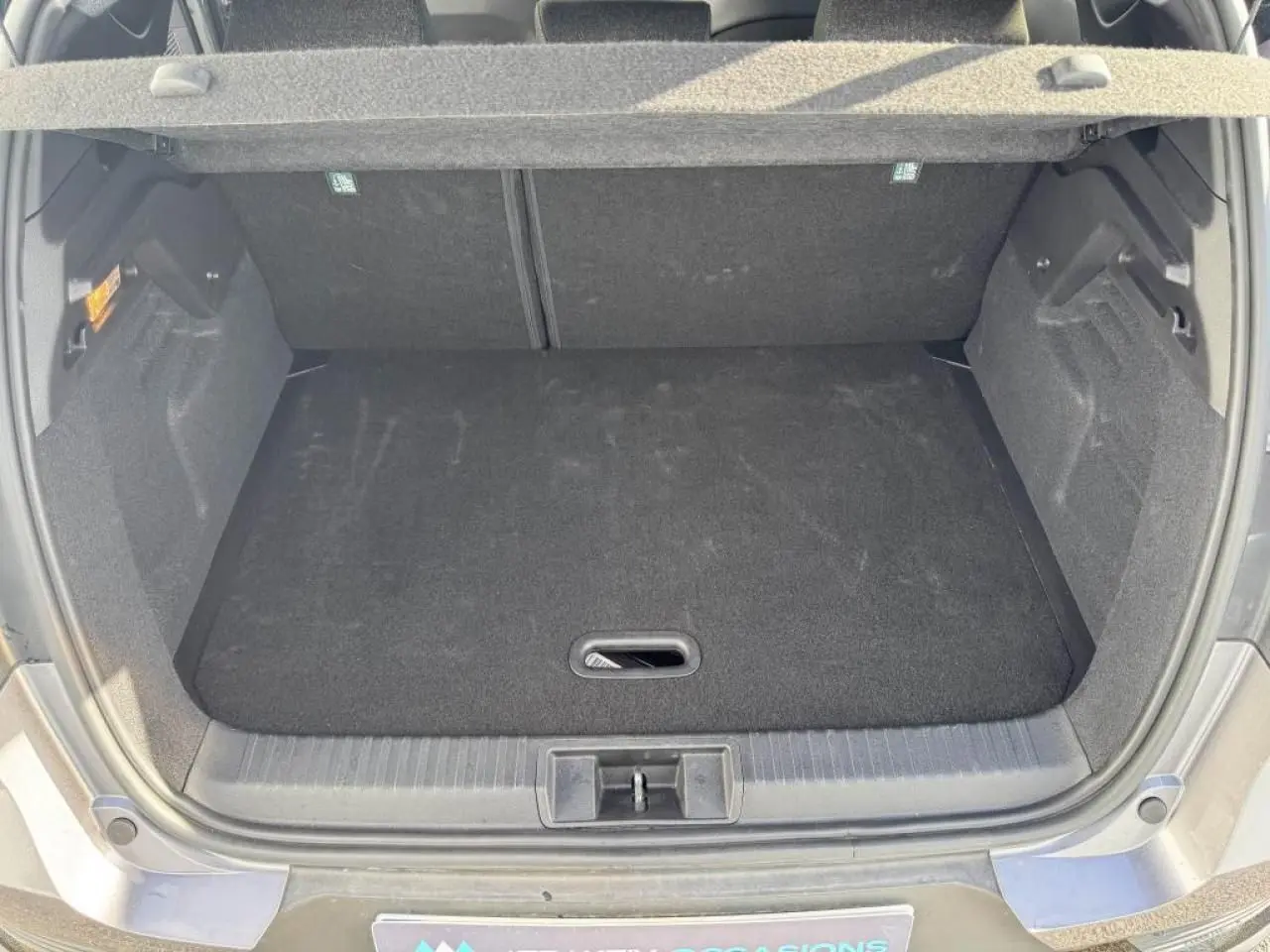 Coffre ouvert vu de l'arrière du Renault Captur gris Cassiopée avec plancher de coffre mobile et intérieur noir.