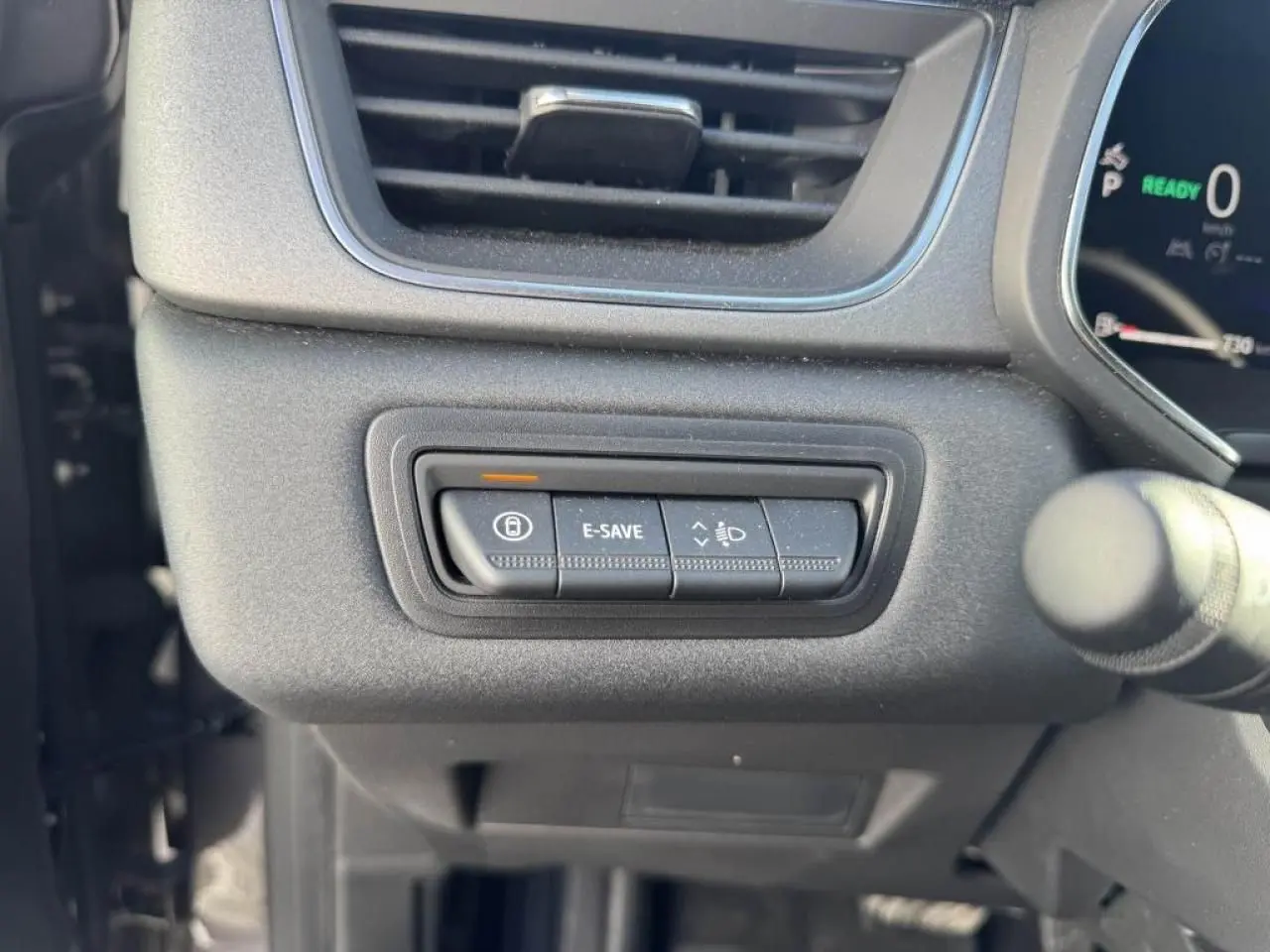 Gros plan sur les commandes situées à gauche du volant du Renault Captur II gris Cassiopée, avec bouton E-SAVE allumé.