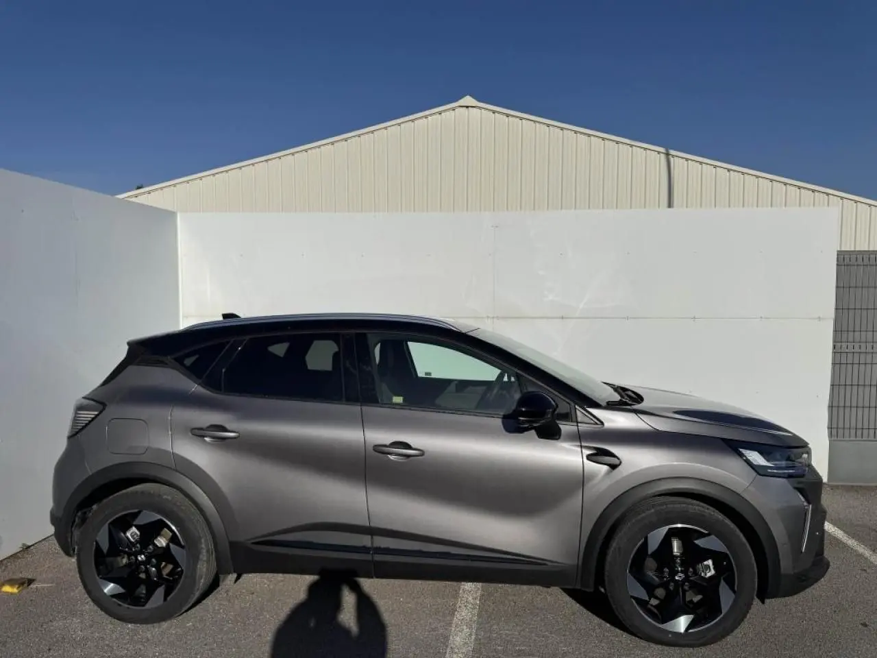 Renault Captur II gris Cassiopée avec toit noir, vue de profil côté gauche, jantes noires distinctives.