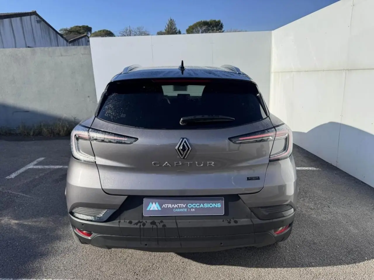 Vue arrière d'un Renault Captur gris Cassiopée avec toit noir, feux LED et logo bien visibles.