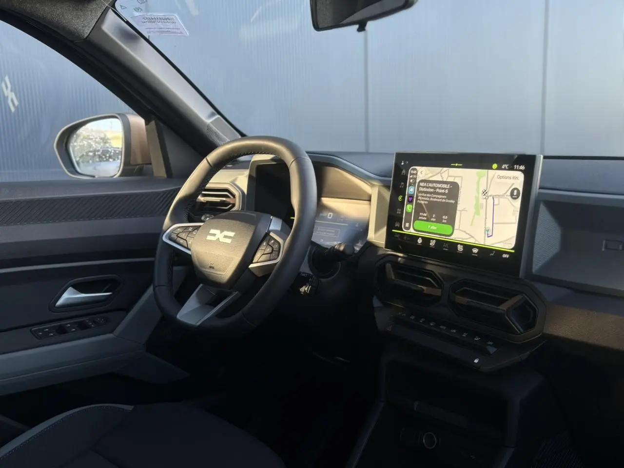 Vue intérieure côté conducteur du Dacia Duster 2025 avec volant multifonction, écran tactile GPS et détails brun cuivré.