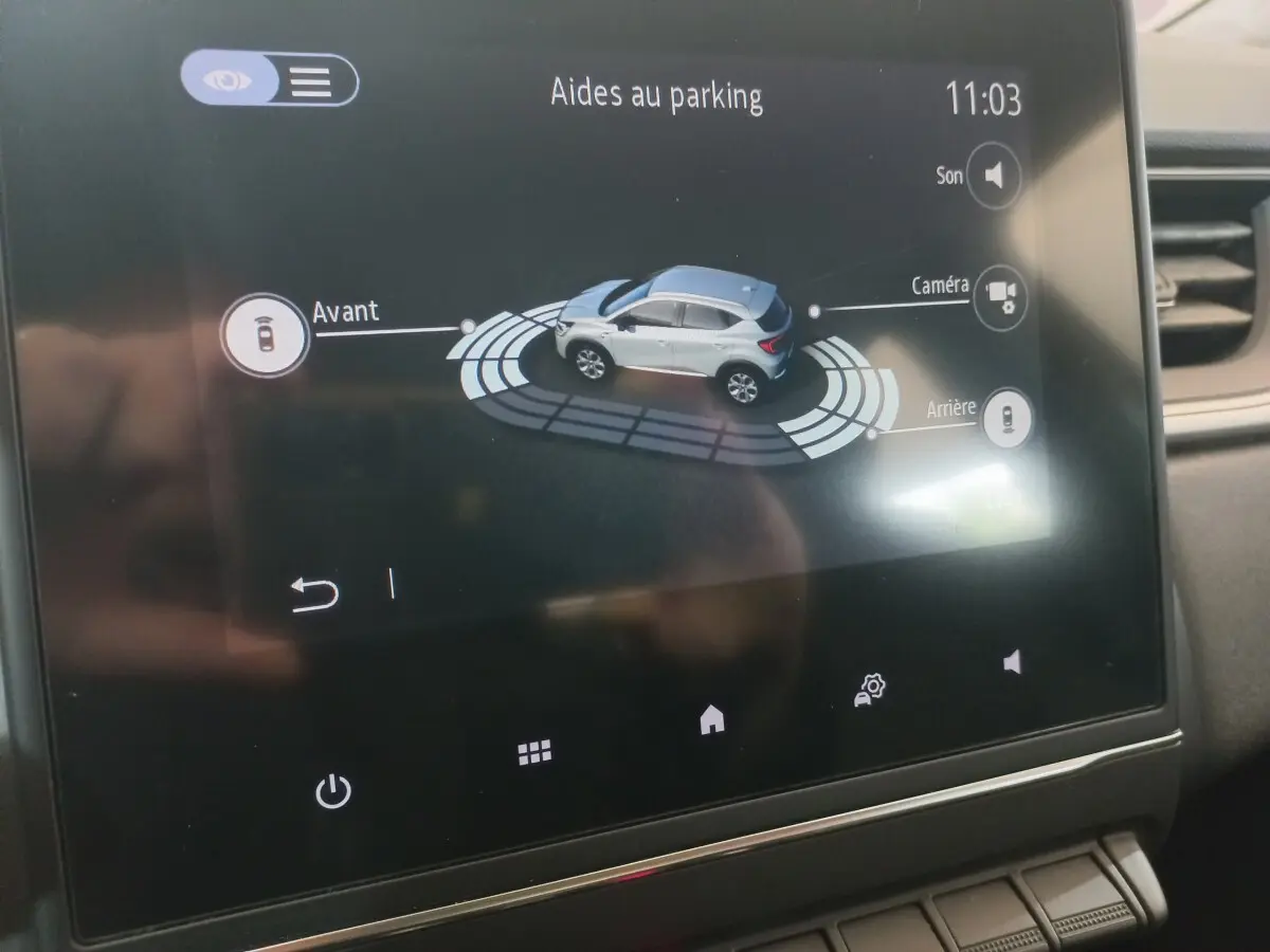 Écran tactile intérieur du Renault Captur Business TCe 100 montrant l'aide au parking avec vue 3D du véhicule gris clair.