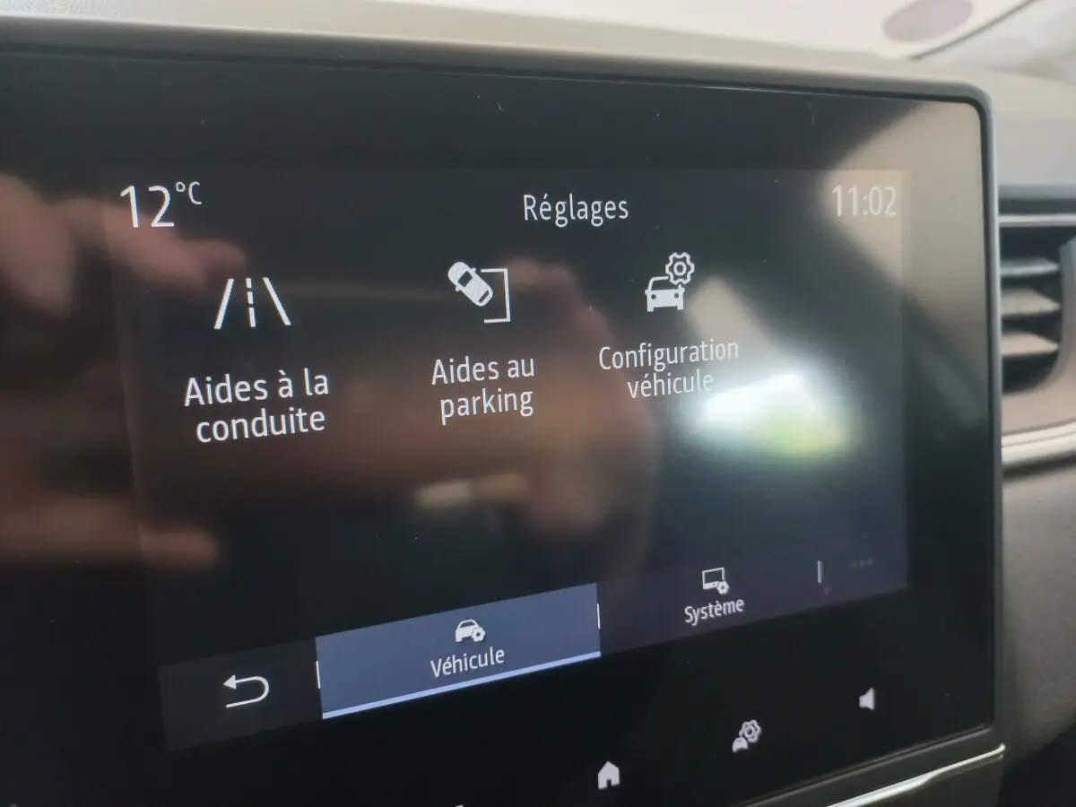 Écran tactile central du tableau de bord du Renault Captur Business TCe 100 affichant les réglages d'aides à la conduite et au parking.