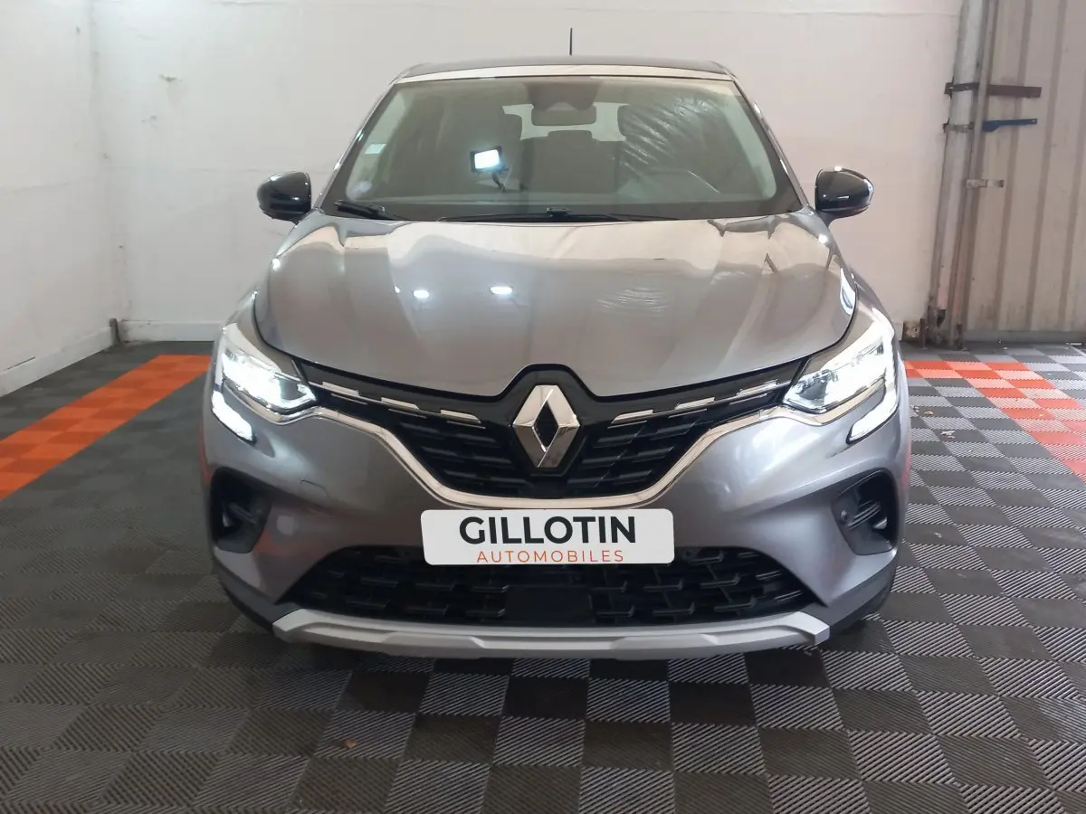 Vue frontale d'un Renault Captur Business TCe 100 gris clair avec feux LED allumés et calandre noire brillante.