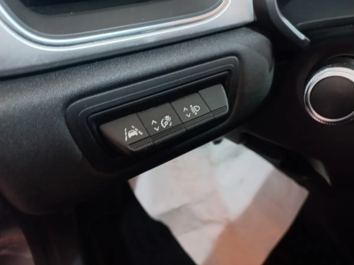 Gros plan sur les boutons de réglage d'assistance et éclairage du tableau de bord noir du Renault Captur Business gris clair.