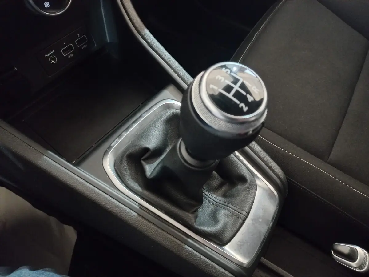 Le levier de vitesse manuel noir du Renault Captur Business TCe 100 2020, entouré de garnitures chromées et tissu noir.