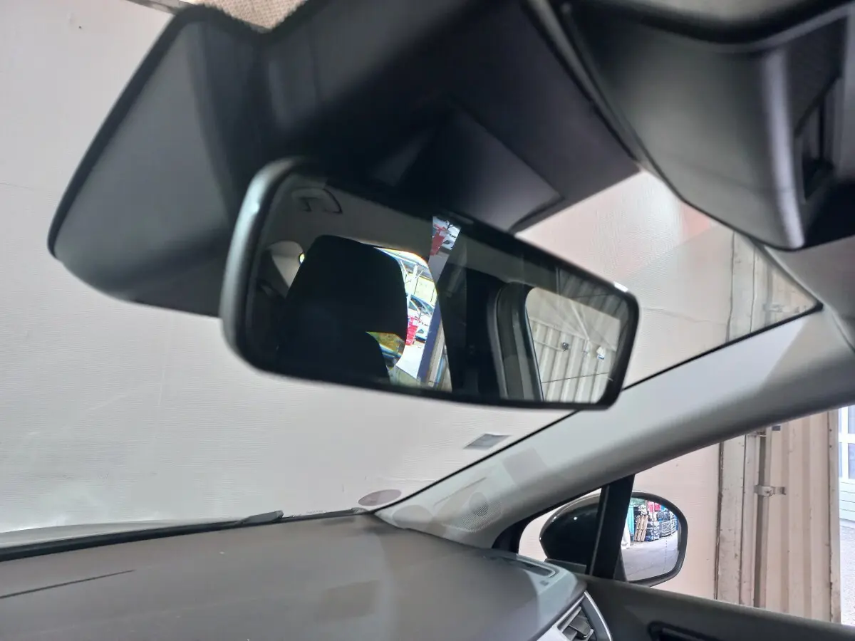 Vue intérieure du rétroviseur central et du tableau de bord gris clair du Renault Captur Business TCe 100, angle avant droit.