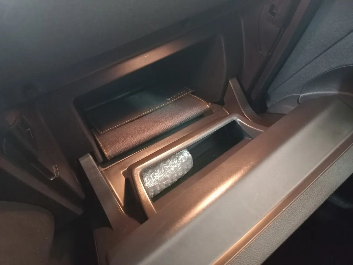 Gros plan sur la boîte à gants ouverte du Renault Captur Business gris clair, avec un étui en cuir marqué Renault.