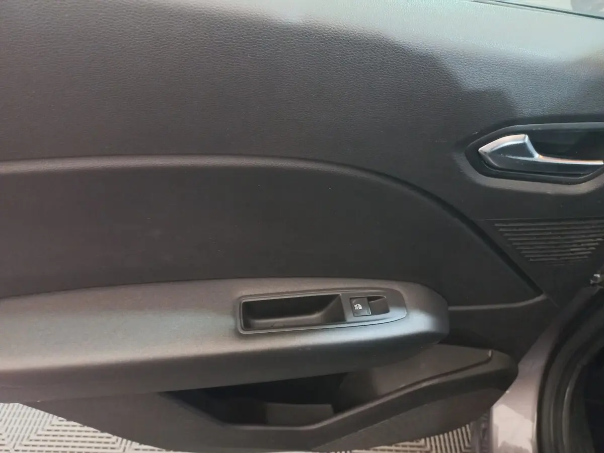 Gros plan sur la porte côté droit du Renault Captur gris clair 2020, montrant la poignée intérieure et le bouton de verrouillage des vitres.