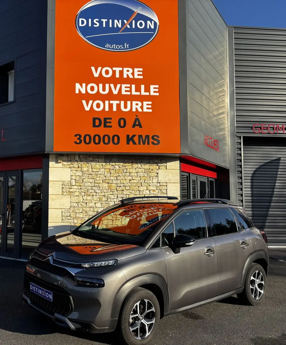Citroën C3 Aircross gris foncé vue 3/4 avant droit, avec barres de toit noires et jantes alliage distinctives.