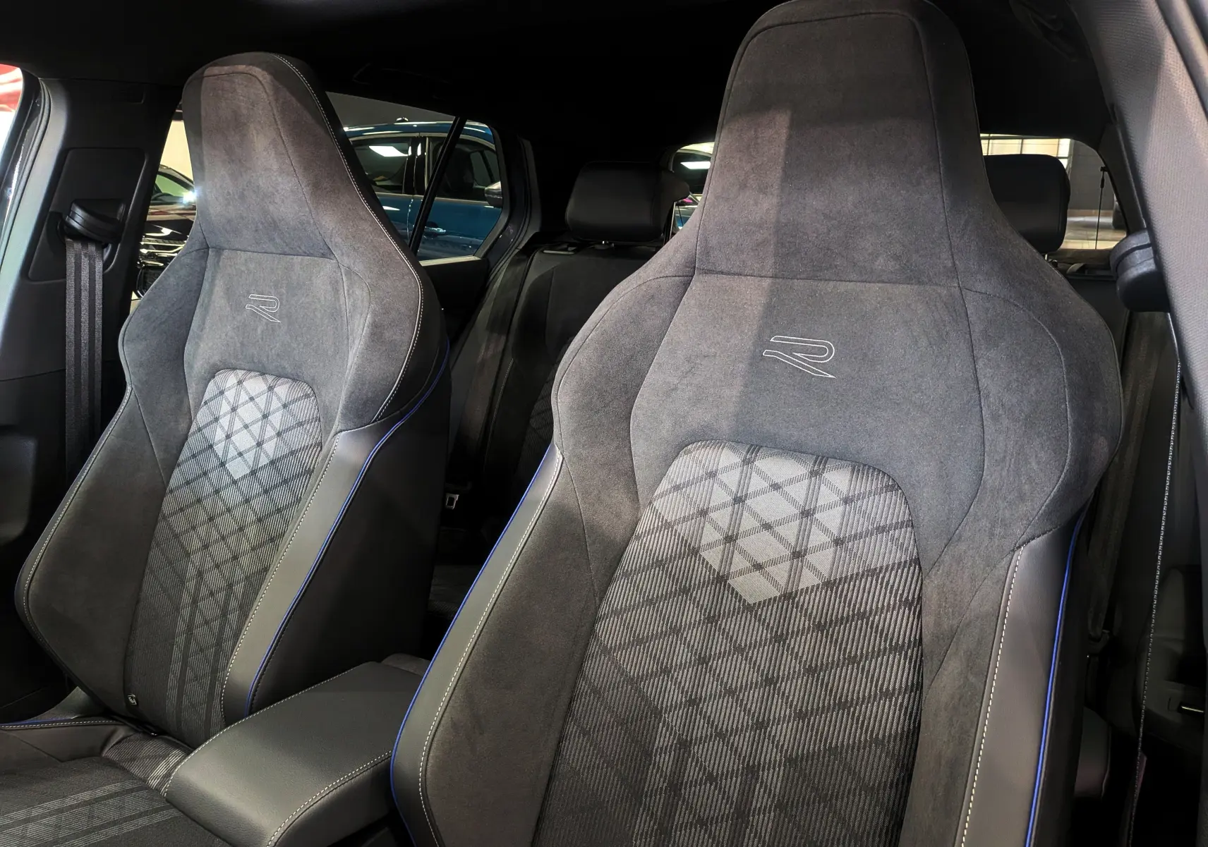 Gros plan sur les sièges avant en tissu gris et alcantara avec logo R, intérieur d'une Volkswagen Golf 2025.
