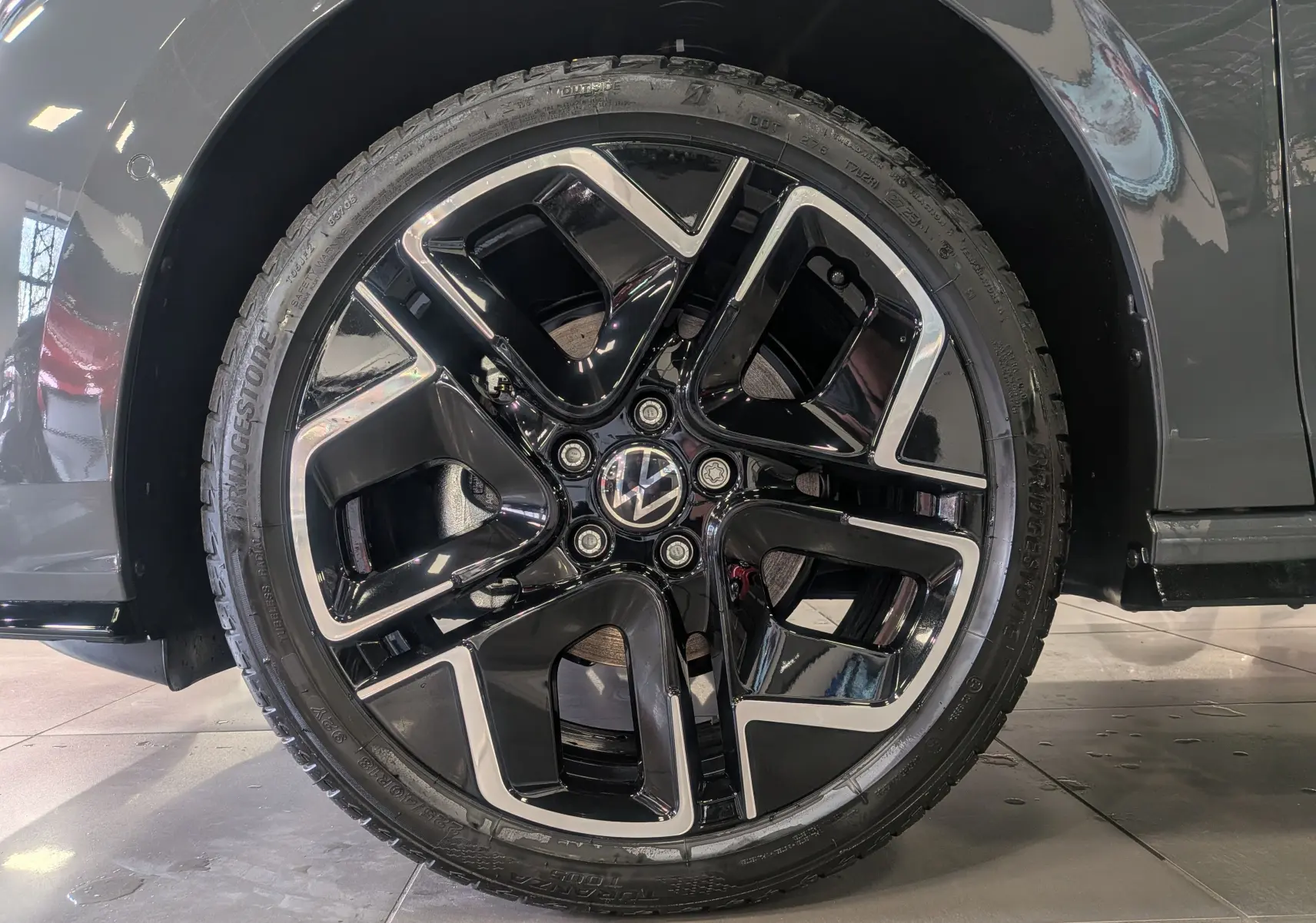 Gros plan sur la jante noire et argentée d’une Volkswagen Golf gris dauphin, côté droit du véhicule.