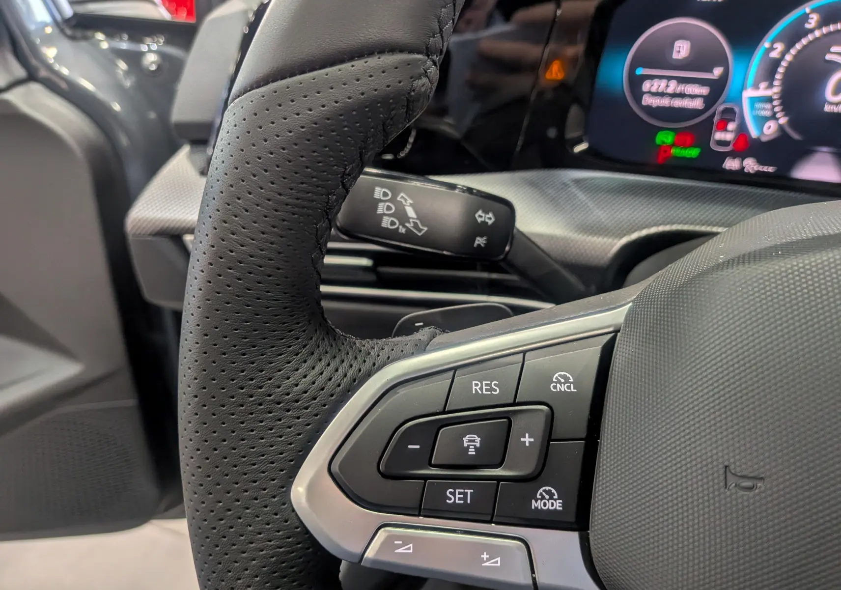 Gros plan sur le volant en cuir perforé et les commandes de régulateur de vitesse d'une Volkswagen Golf 2025.