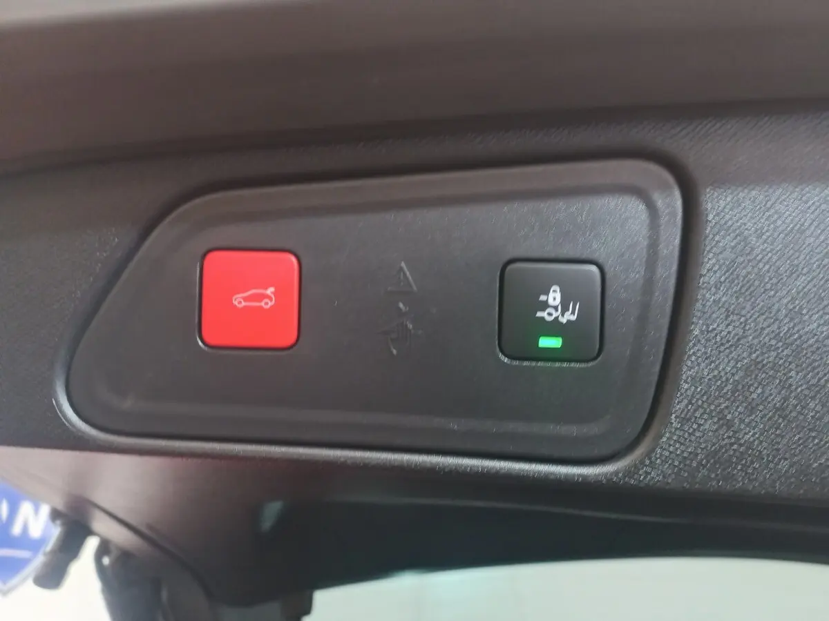 Gros plan sur les boutons d'ouverture et de verrouillage électrique du coffre dans un Peugeot 3008 gris clair 2022.