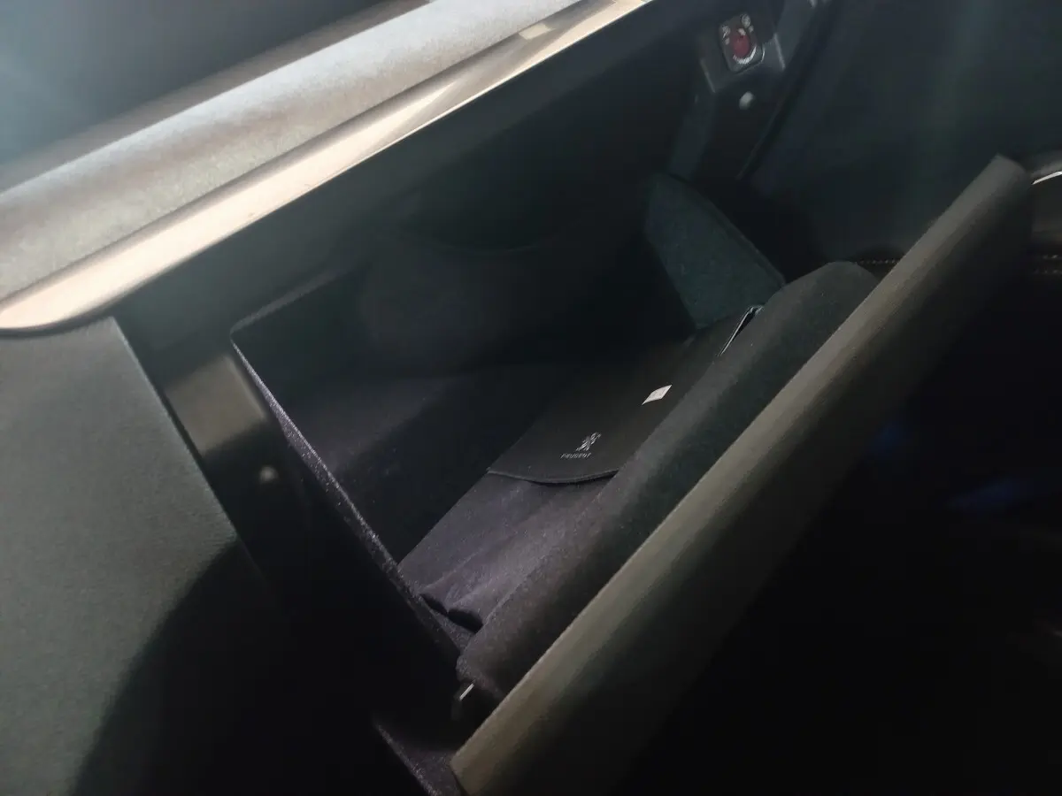 Vue rapprochée de la boîte à gants ouverte du Peugeot 3008 gris clair, montrant un étui noir à l'intérieur.