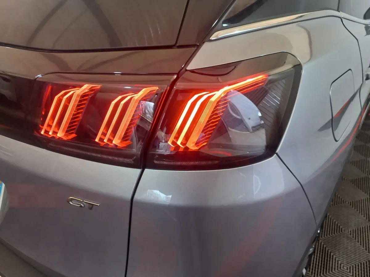 Feu arrière droit allumé d’un Peugeot 3008 GT gris clair, vue rapprochée sur la partie arrière droite.
