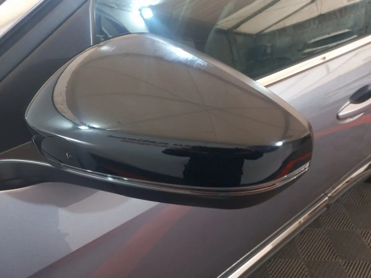 Gros plan sur le rétroviseur droit noir brillant du Peugeot 3008 gris clair, avec partie de la portière visible.