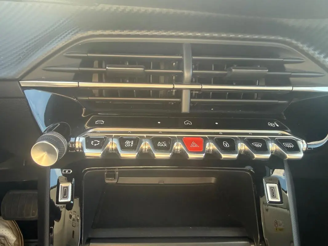 Vue rapprochée de la console centrale du Peugeot 208 Hybrid blanc 2024, avec boutons de commande et aérateurs noirs.