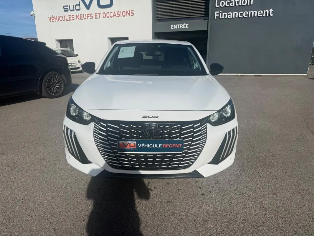 Vue de face d'une Peugeot 208 Hybrid 110 e-DCS6 Allure blanche 2024 avec calandre noire et phares LED distinctifs.