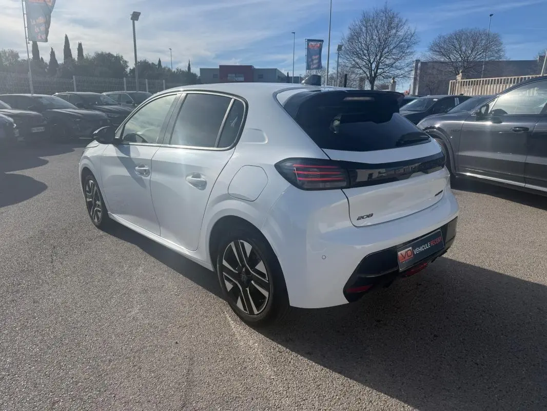 Peugeot 208 Hybrid blanc vue 3/4 arrière droit, feux arrière LED et jantes alliage distinctives visibles.