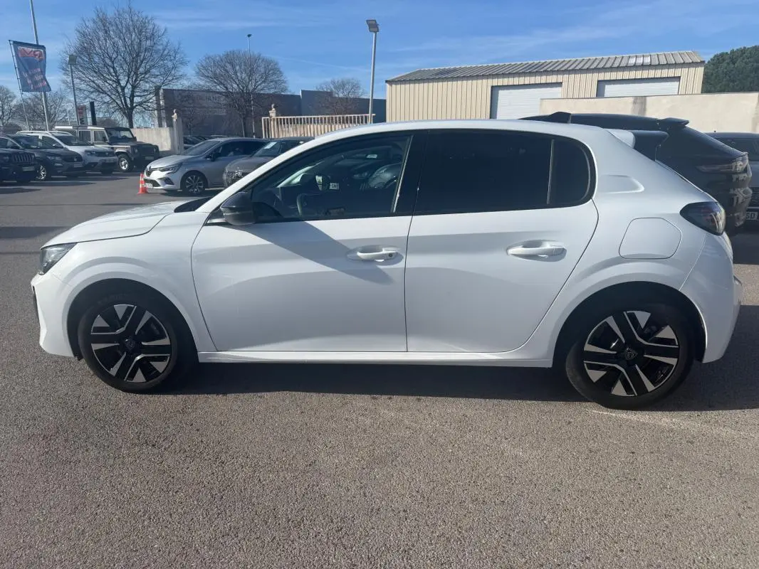 Peugeot 208 Hybrid blanc vue de profil côté gauche, avec jantes noires et détails modernes visibles.
