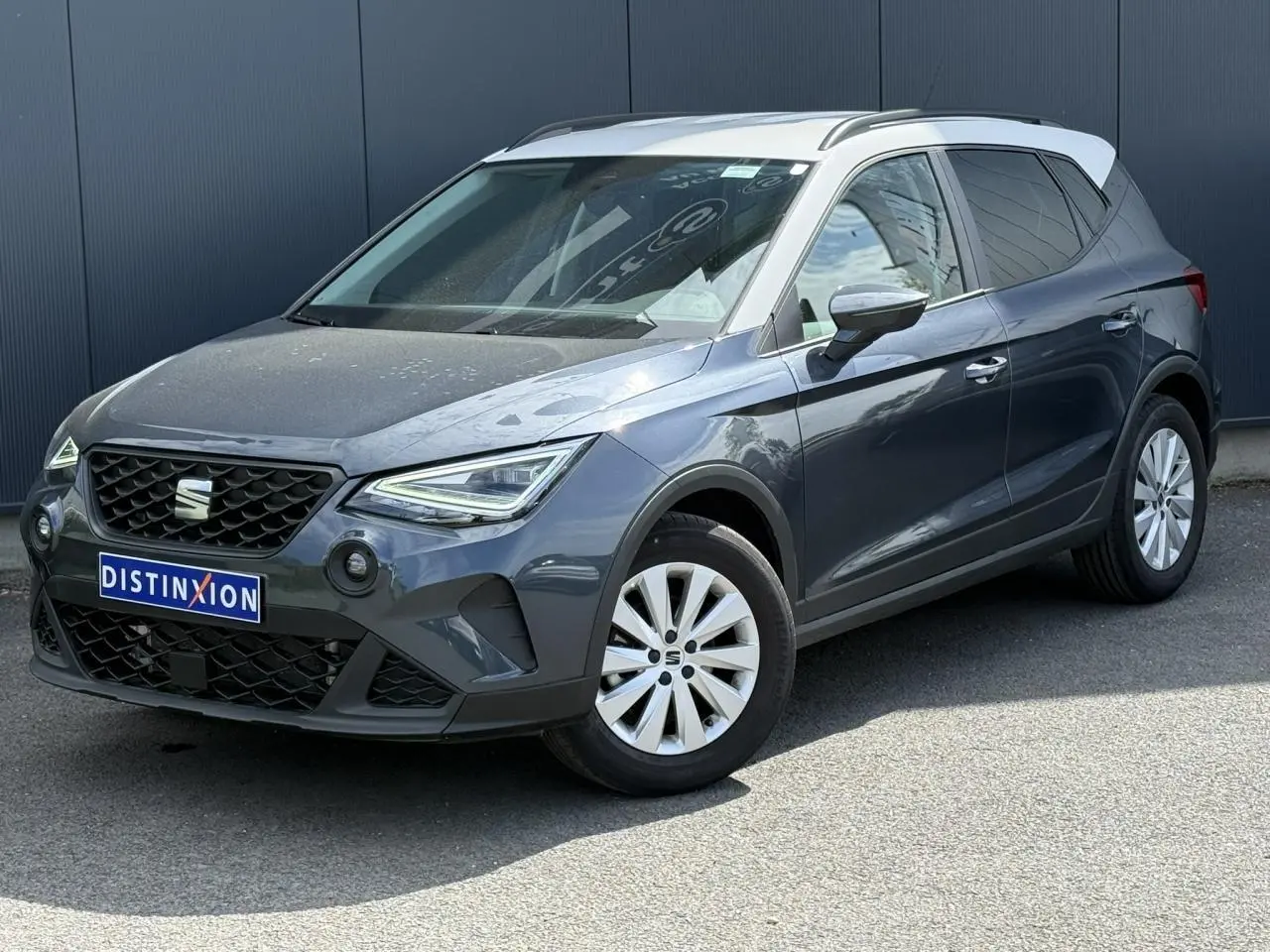 SEAT Arona TSI 115 Style 2025 en gris magnétique avec toit blanc, vue 3/4 avant droit sur fond urbain.